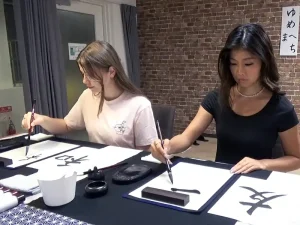 Guests practicing Japanese calligraphy in Kyoto